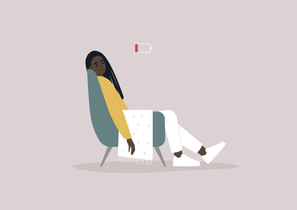 woman lay exhausted in a chair with a low battery above her head